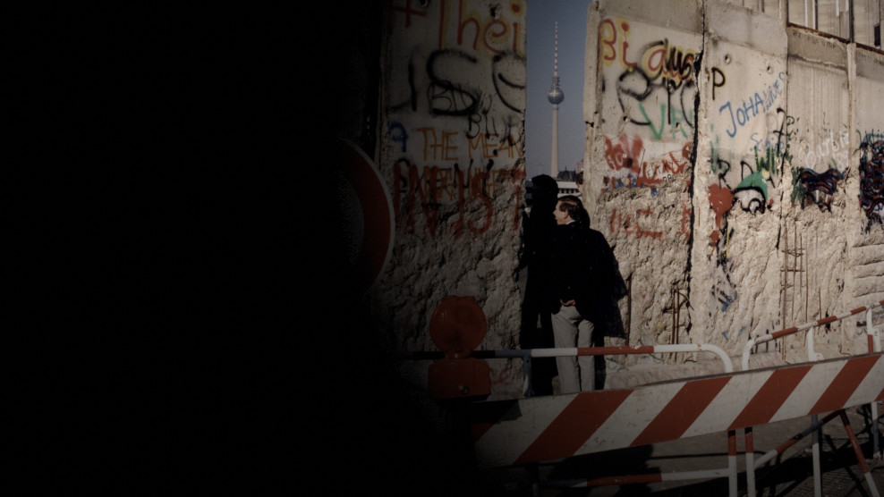 Personen gehen durch Lücke in der Berliner Mauer